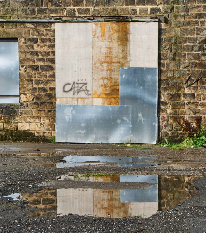 boarded wondow reflected in puddle