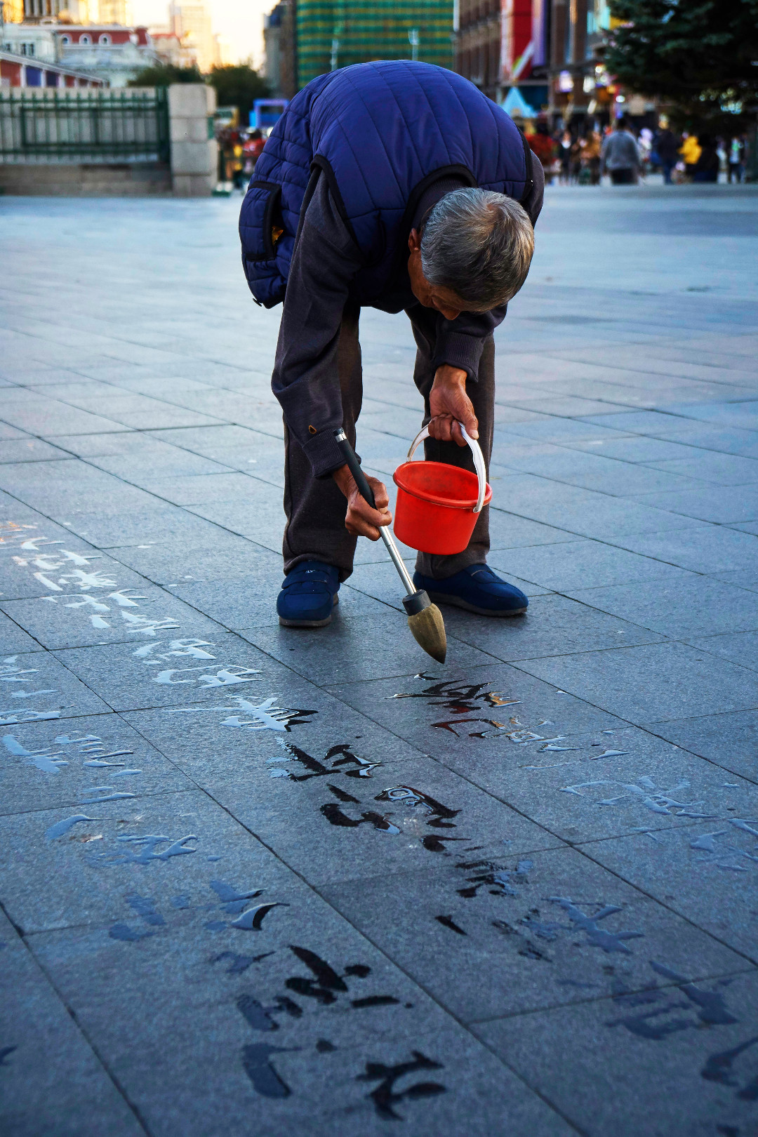 Man writing chinese characters on pavement