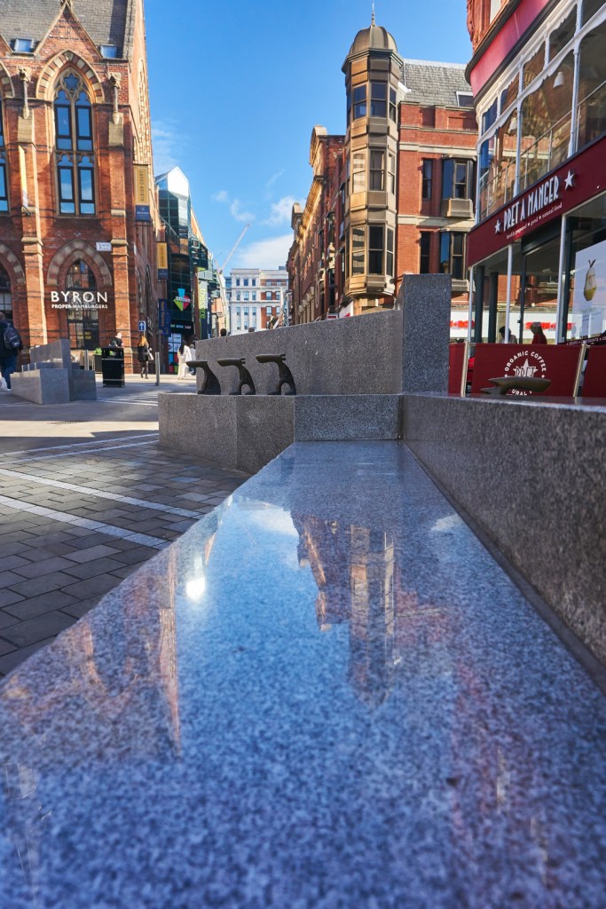 Leeds city centre reflected on granite bench