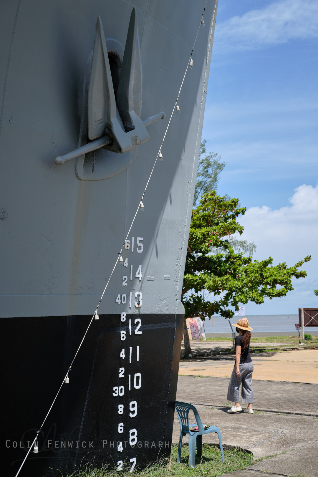 Tourist walks past the bow of HTMS Prasae
