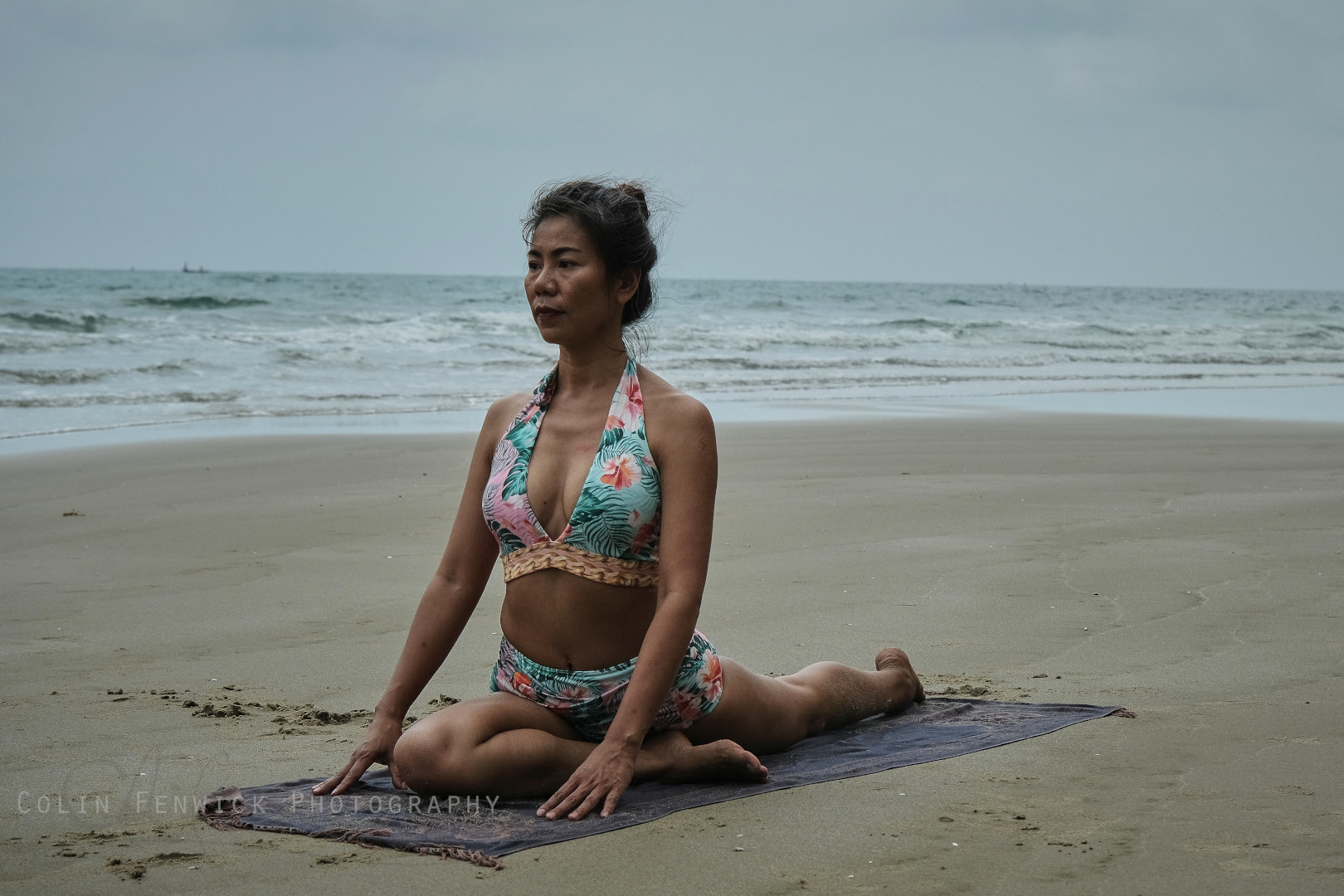 Woman practising Yoga pigeon pose on a beach