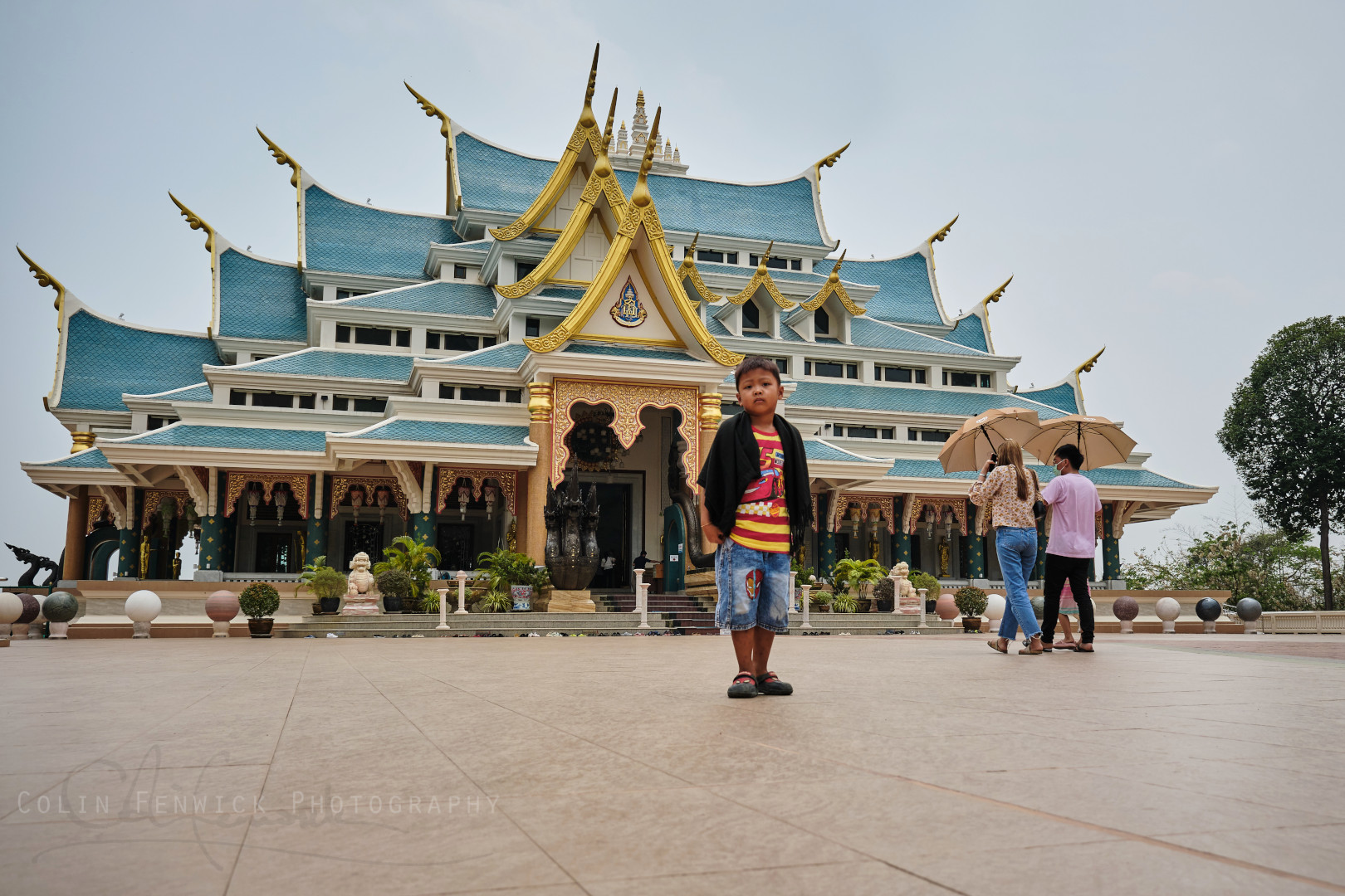 Boy stands in front of the temple at Wat Pa Phu Kon, Udon Thani, Thailand